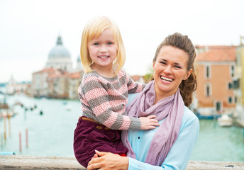 Fototapeta na wymiar Portrait of smiling mother and baby girl standing on bridge 