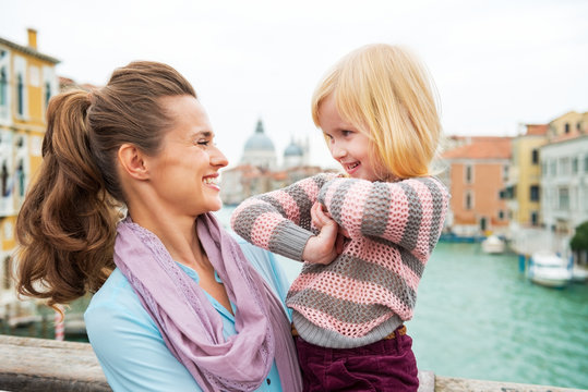 Mother and baby girl on bridge with grand canal in venice, italy