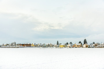 snow covered fields with settlement at the horizon in Munich
