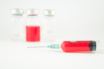 Red liquid in injection syringe and vials