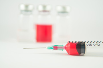 Red liquid in injection syringe and vials background