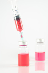 Red liquid in injection syringe and vials