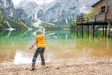 Child throwing stones on lake braies in south tyrol, italy