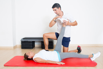 Trainer hilft Rentnerin mit einer Dehnuebung