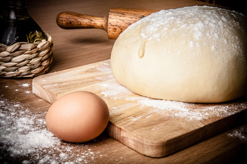 Fototapeta premium dough on a board with flour. olive oil, eggs, rolling pin