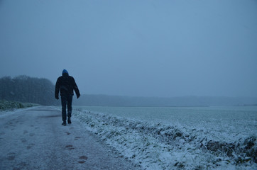 man walking in snowy meadow