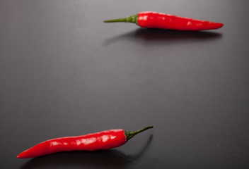 Two red chili peppers on a dark background