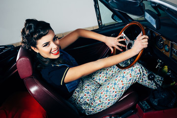 Naklejka na ściany i meble Smiling young woman in vintage car