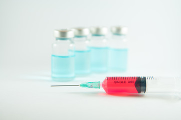 Red liquid in injection syringe and vials background