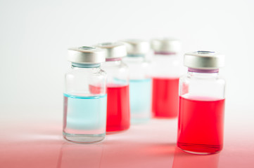 Red and blue liquid in injection vials on red floor effect
