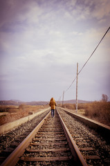 Young woman walking on a railway. Rural setting