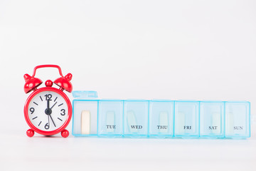 weekly pill box and red clock show medicine time