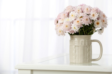 Beautiful bouquet of flowers in cup on window background
