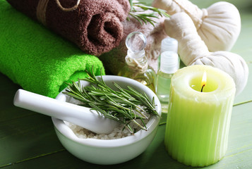 Branches of rosemary and sea salt in bowl, towels, candle and