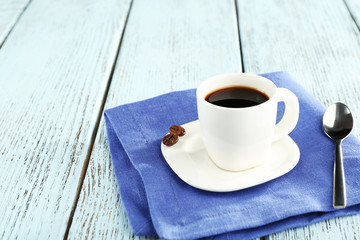 Cup of coffee on blue napkin on color wooden background