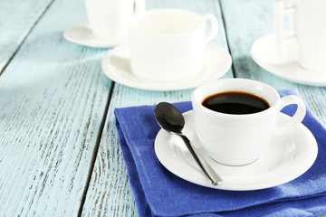 Cup of coffee with other cups on color wooden background
