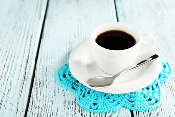 Cup of coffee on lace doily on color wooden background