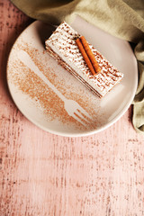Tasty tiramisu cake on plate, on wooden table