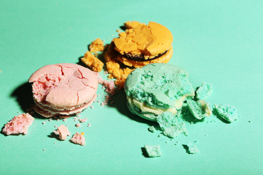 Bright tasty broken macaroons cakes on color background