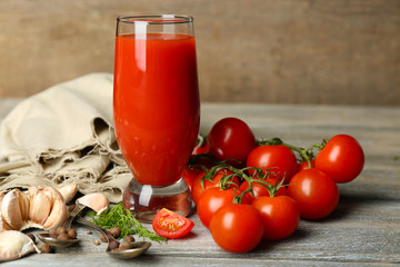 Glass of tasty tomato juice and fresh tomatoes on wooden table