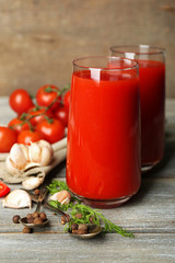Glasses of tasty tomato juice and fresh tomatoes on wooden