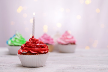 Delicious birthday cupcakes on table on light background