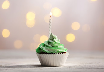 Delicious birthday cupcake on table on light background