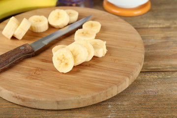 Fototapeta na wymiar Sliced banana on cutting board, on wooden background