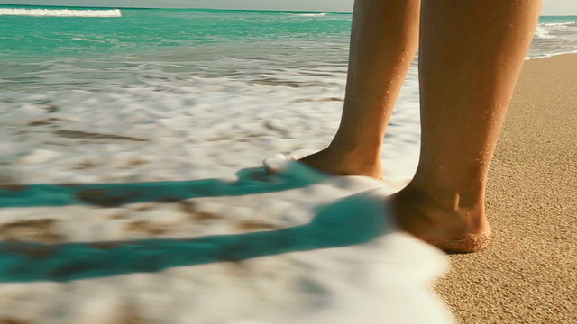 Ocean waves washing over woman's feet