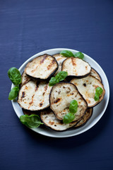 Close-up of grilled aubergine with green basil, vertical shot