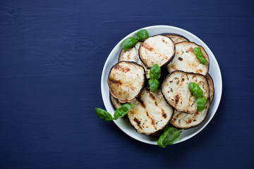Grilled aubergine slices, dark blue wooden surface, above view