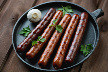 Grilled sausages with parsley and garlic in a frying pan