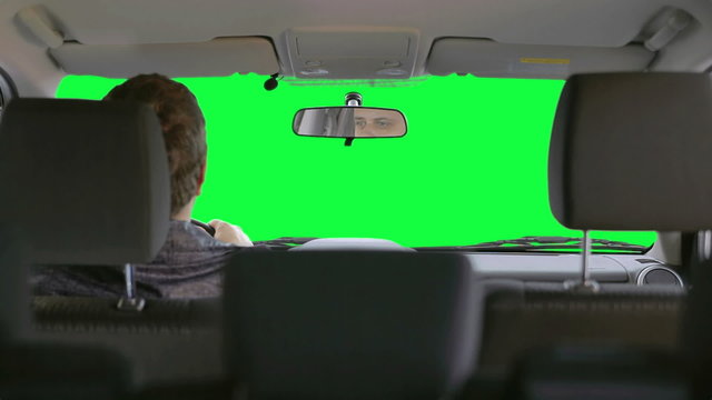 Man drives a car against a green background