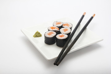 Plate of salmon maki sushi with chopsticks and wasabi