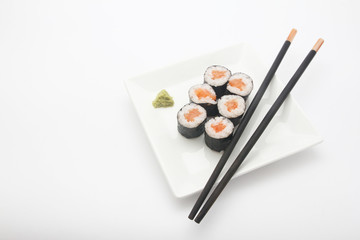 Plate of salmon maki sushi with chopsticks and wasabi