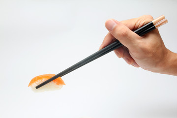 Hand holding salmon sushi with chopsticks