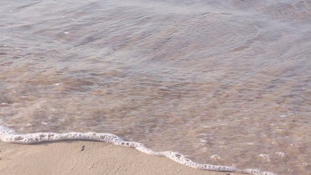 Mother helping his little son making first steps on the beach
