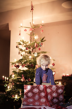 Kleiner Junge freut sich vor dem Christbaum &uuml;ber sein Geschenk