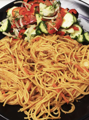 Tomatoa pasta on plate with fresh basil leaves