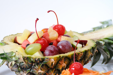 Fruits salad in pineapple on white plate, food stylist