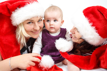 smiling infant baby with two womans with santa hats