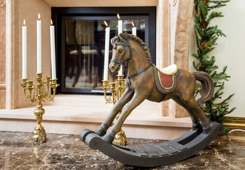 Fototapeta na wymiar Old wooden rocking horse near the fireplace
