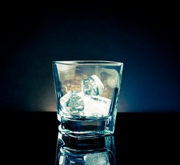 empty whiskey glass with ice and light tint blue disco