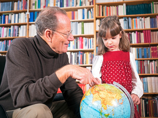 Großvater und Enkeltochter betrachten einen Globus