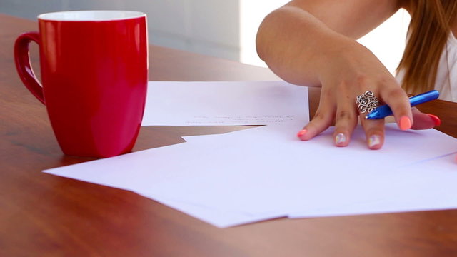 Wind blows sheets of paper while woman is writing