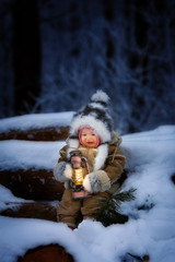 A small child in the winter woods with a lantern