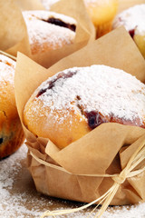 Muffins with jam sprinkled with powdered sugar on wooden tray