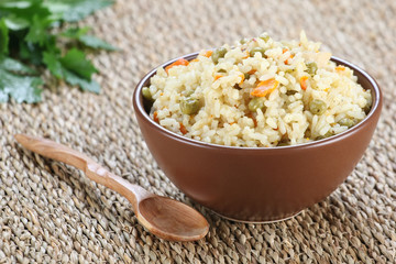 rice with vegetables in a ceramic bowl on a mat