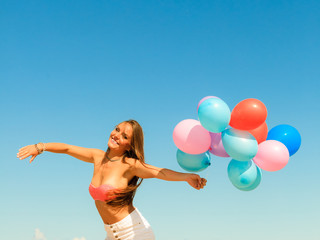 Girl jumping with colorful balloons on beach