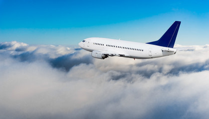 Naklejka na ściany i meble Passenger airplane flying above dramatic clouds